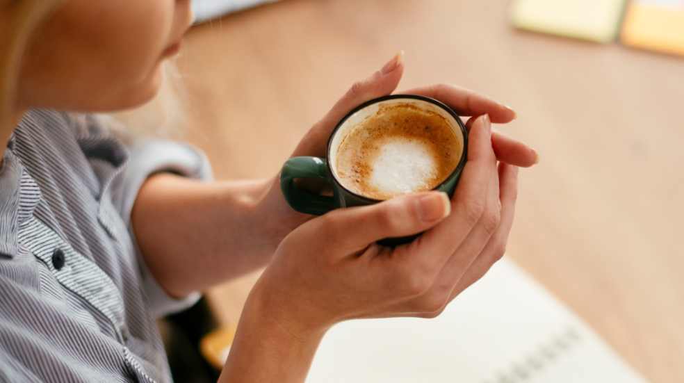 Inflammation and Coffee Woman holds coffee to illustrate link between inflammation and coffee